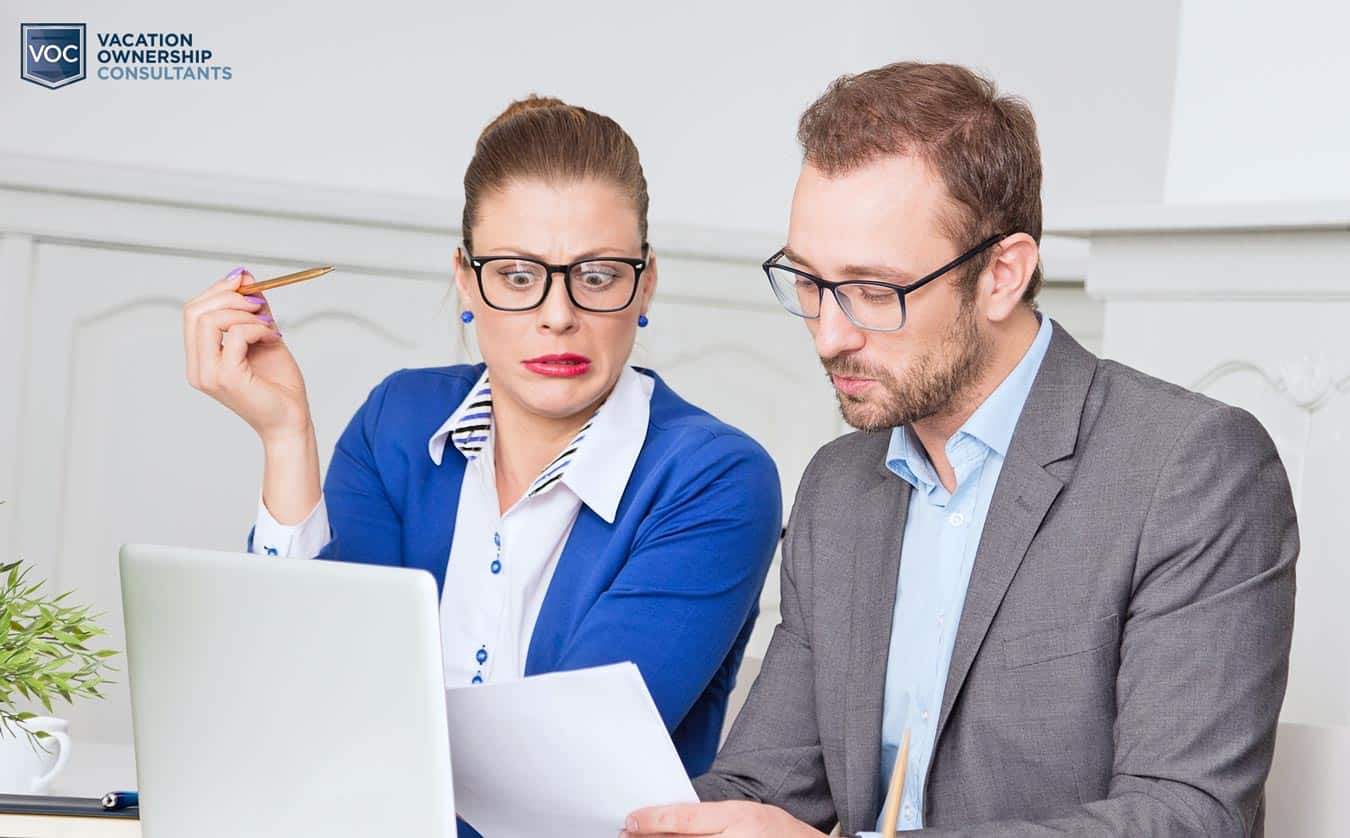 disgusted-confused-look-on-woman-in-blues-face-while-looking-at-paperwork-to-get-rid-of-timeshare-purchases-clueless-with-partner