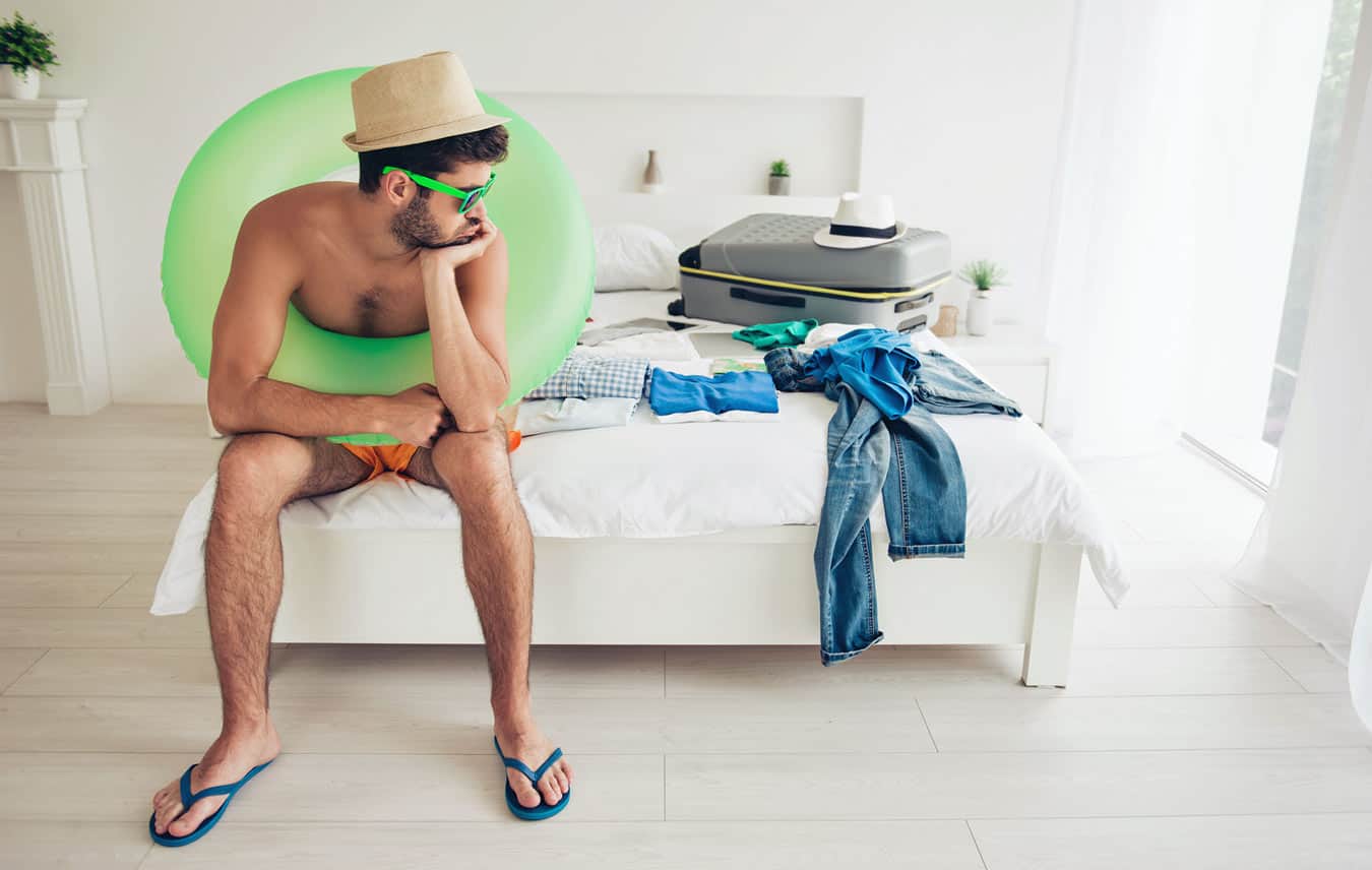 young-guy-sitting-on-vacation-bed-waiting-to-book-perfect-timeshare-reservation