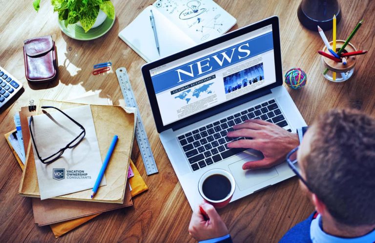 heaven-shot-of-of-desk-where-man-is-looking-at-res-releases-by-timeshare-companies-on-laptop-computer