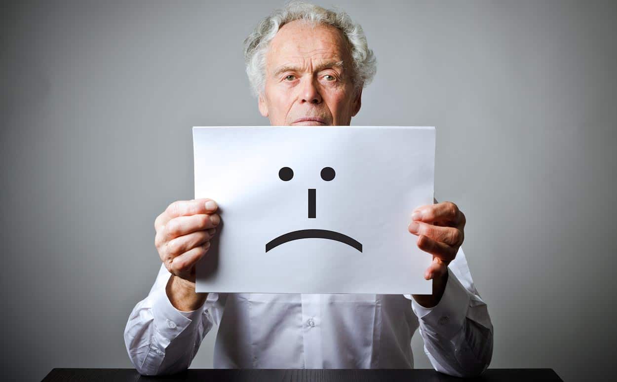 aging-man-wrinkled-shirt-holding-sad-face-sign-to-exemplify-unhappiness-with-timeshare-loans