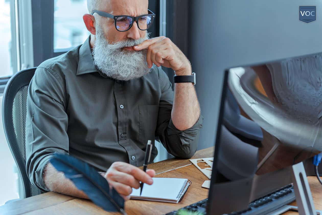 bearded-man-studying-computer-in-office-reading-timeshare-exit-reviews-online