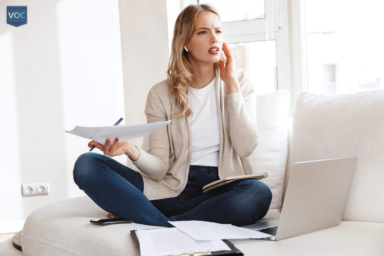 younger-blonde-woman-on-phone-by-computer-and-bills-arguing-liability-of-timeshare-after-parents-passed-away