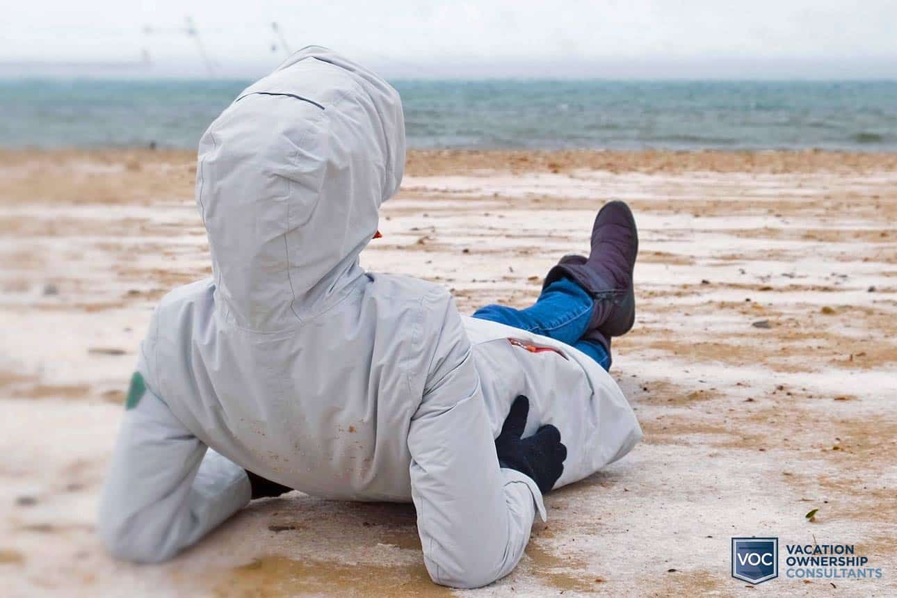 person-on-desolate-beach-no-waves-in-winter-jacket-attire-having-terrible-vacation-alone-thank-to-timeshare-spending-habits