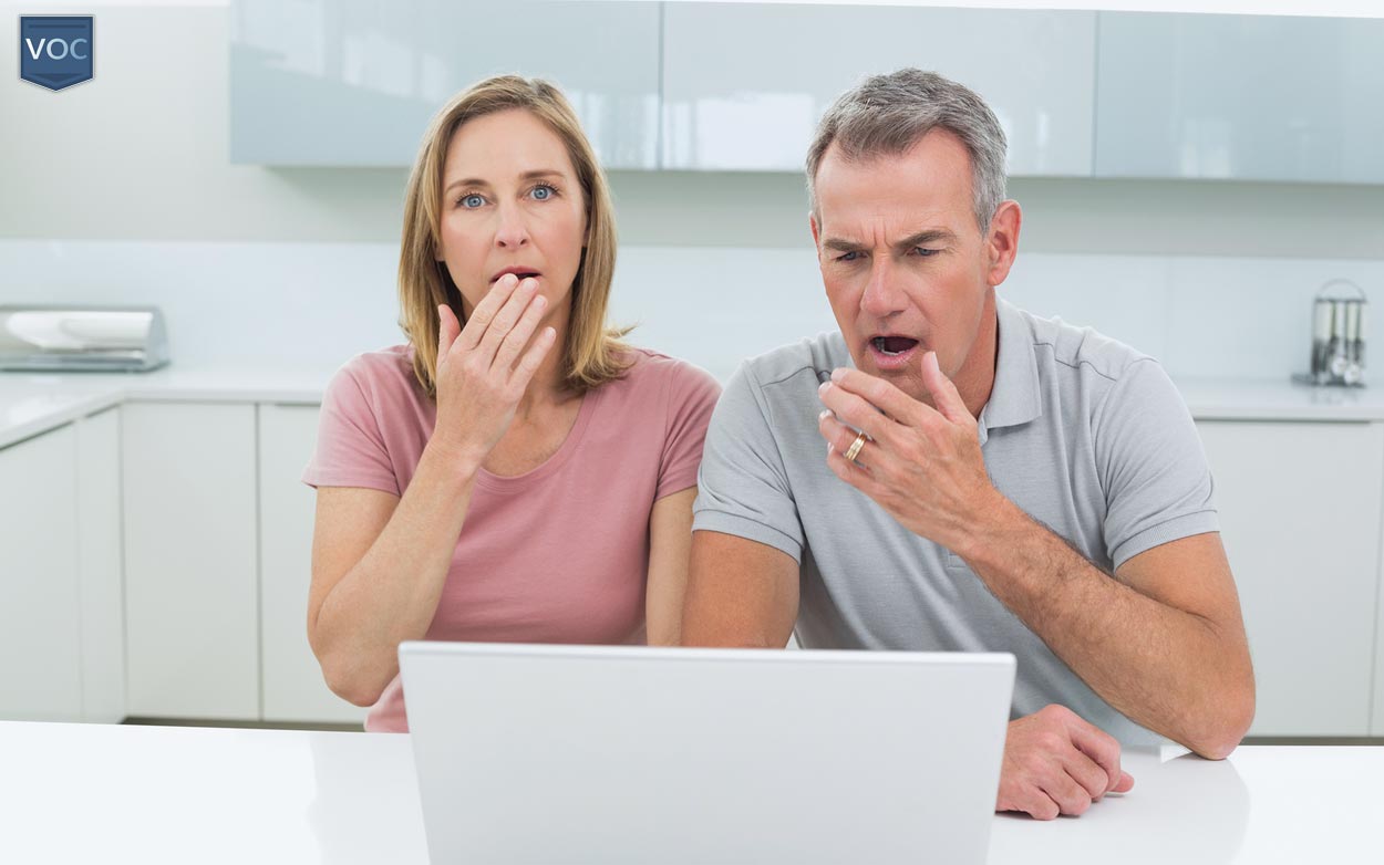 husband-and-wife-in-bland-kitchen-to-capture-facial-expressions-and-colors-during-revelation-on-laptop-of-no-traveling