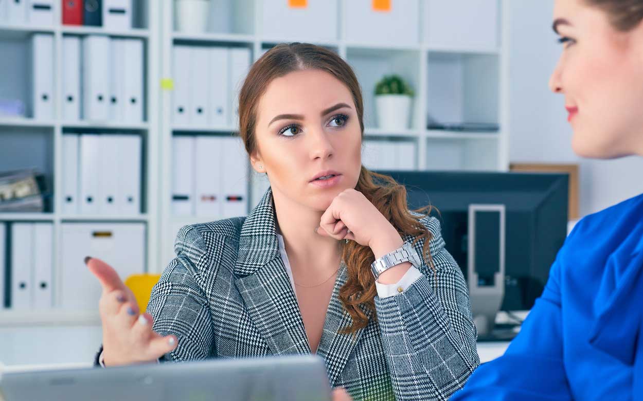 younger-woman-in-business-suit-confused-what-is-being-presented-to-her-by-arrogant-saleswoman-totally-unfair-travel-arragnements