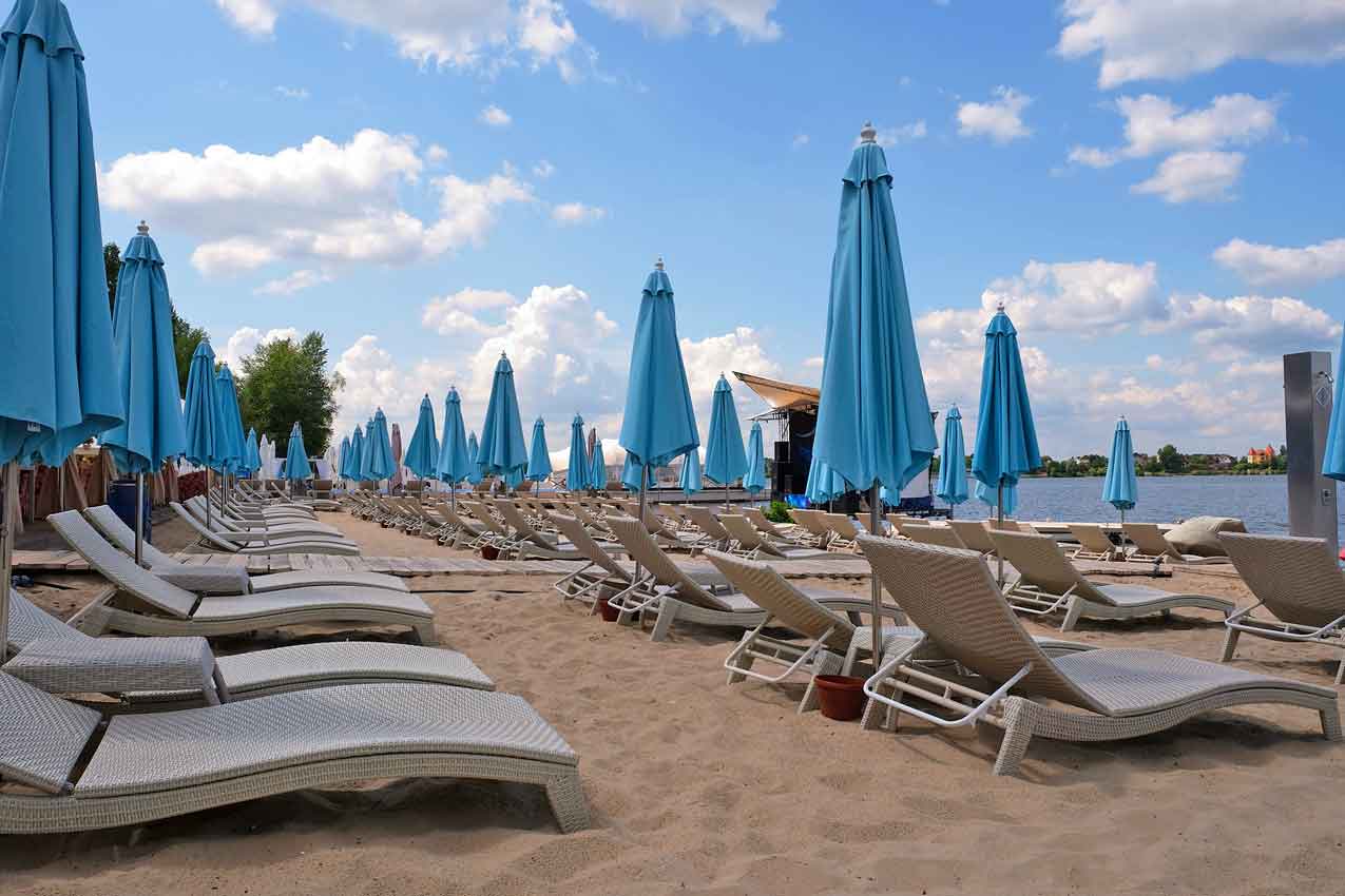 picture-of-beach-flipped-with-navy-blue-umbrellas-closed-empty-lawn-chairs-due-to-viral-disease