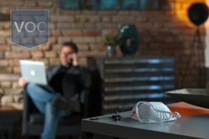 man-in-basement-on-phone-and-computer-relaxing-with-covid-19-protection-mask-on-counter-unable-to-use-marriott-timeshare-owner