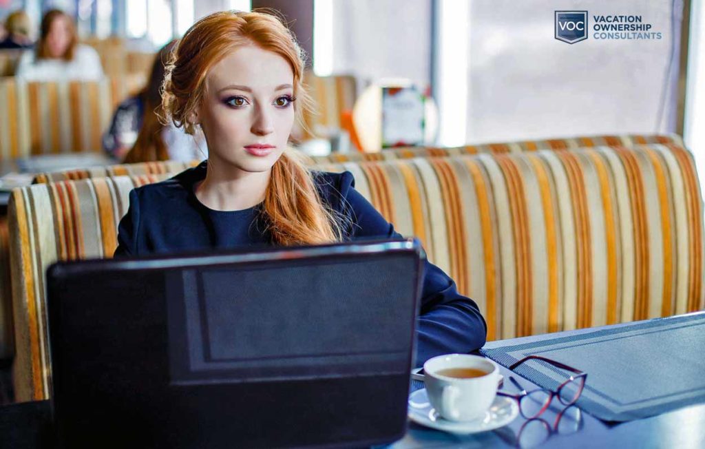 young-redhead-in-booth-at-restaurant-daydreaming-about-something-she-just-read-onlaptop-during-lunch-about-covid-19