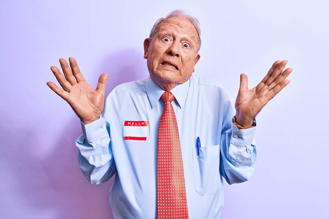 goofy-grandpa-with-name-tag-on-for-timeshare-seminar-getting-pressured-to-buy-backing-off-in-tie-velvet-background