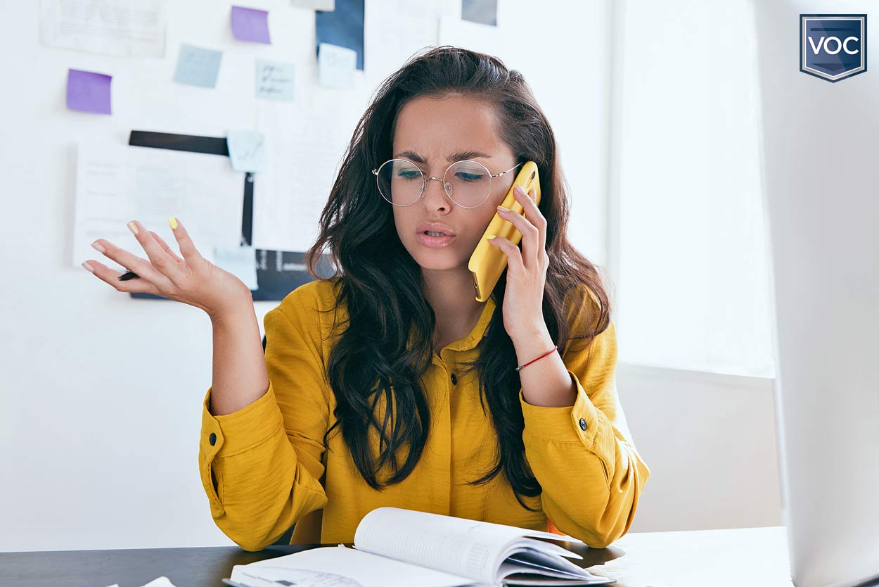 younger-lady-on-phone-in-home-office-during-covid-talking-to-timeshare-company-about-maintenance-bill-when-resort-is-closed-2020