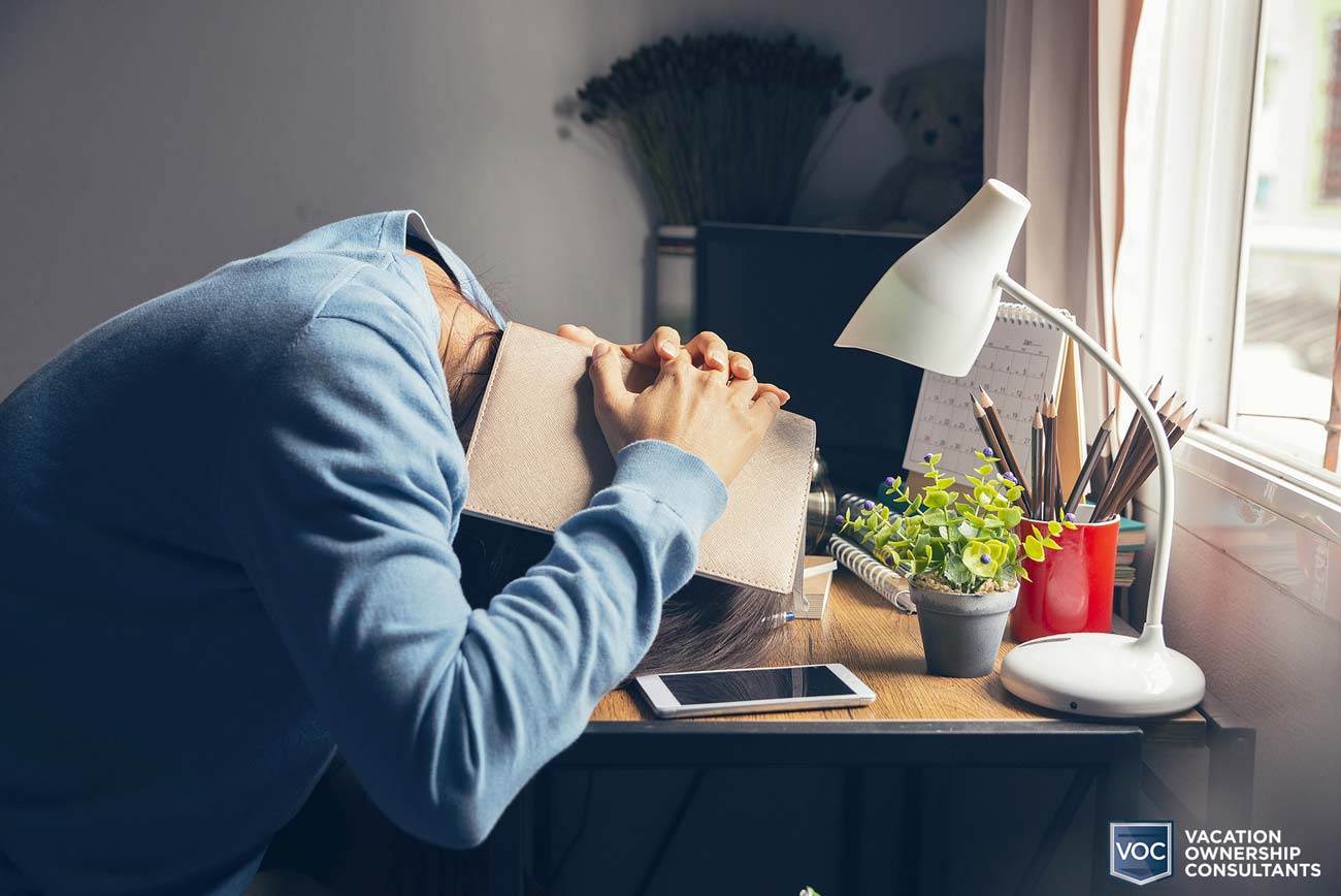 face-down-at-desk-with-paperback-book-over-head-timeshare-expenses-causing-concerns-no-usage-unfair-no-help